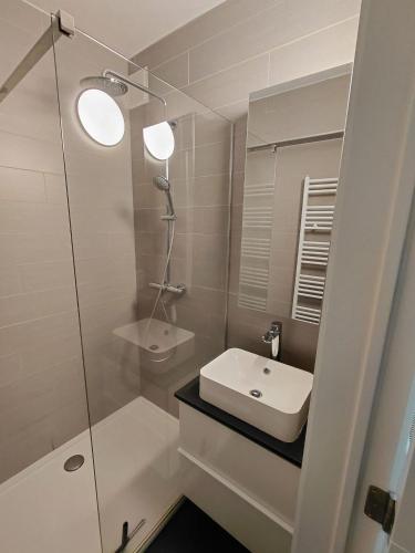 a white bathroom with a sink and a shower at App ZeeVorm Nieuw in De Panne