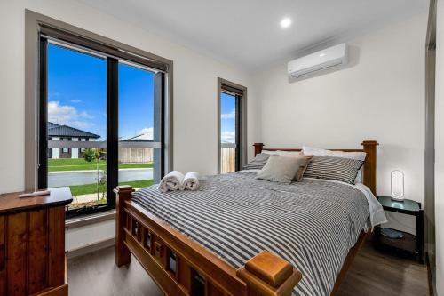 a bedroom with a bed and a large window at IK homes in Clyde North
