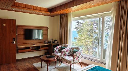 un soggiorno con TV, sedia e finestra di The Retreat Mashobra, Shimla a Shimla