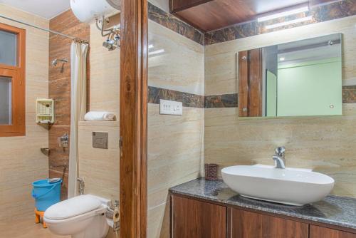 a bathroom with a sink and a toilet and a mirror at Baldeyan Breeze - 2BHK Apartments - Private Balcony in Shimla