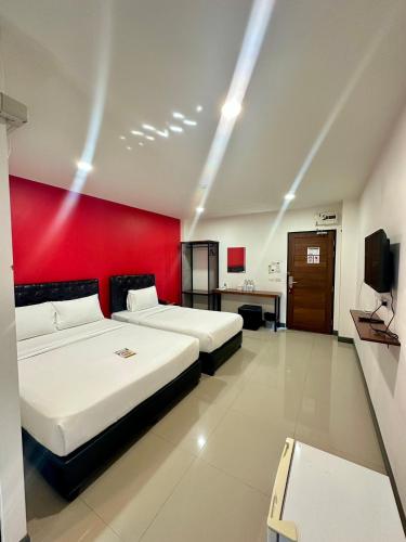 a room with two beds and a red wall at เคทูกรีน สุพรรณบุรี in Ban Hua Phrong