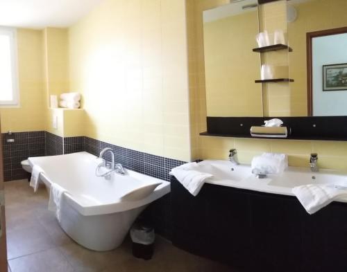 a bathroom with two sinks and a tub and a mirror at Palais Cathare in Bélesta