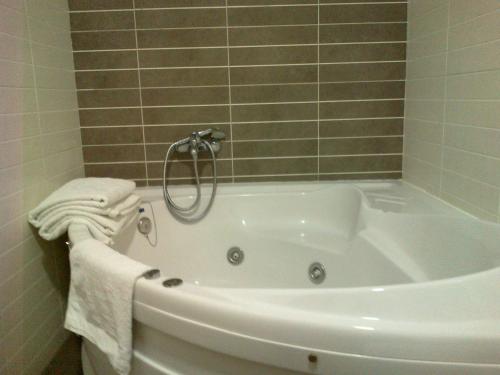 a white bath tub in a bathroom with tiles at Hotel Anabel Baza in Baza