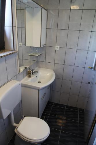 a white bathroom with a toilet and a sink at Holiday Home Mađerka in Štrigova