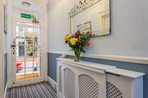 a white vase filled with flowers next to a window at Brighton Surf Guest House in Brighton & Hove