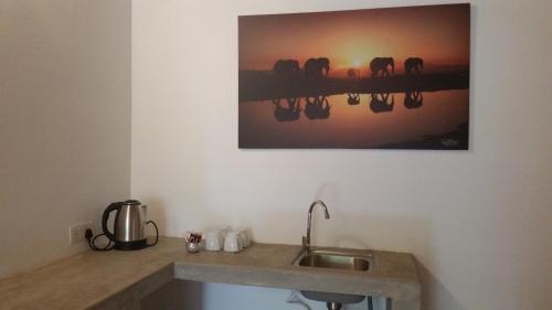 a kitchen with a sink and a painting on the wall at Kutumbaya in Anuradhapura