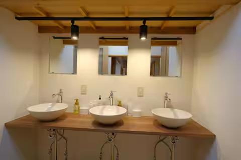 three sinks in a bathroom with three mirrors at 古民家ゲストハウスときわ in Kamakura