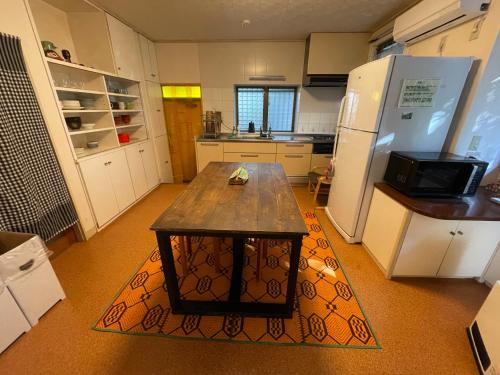 a kitchen with a wooden table and a refrigerator at 古民家ゲストハウスときわ in Kamakura