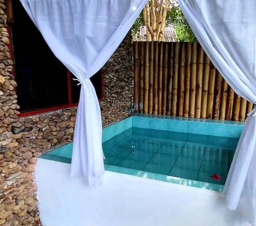 a swimming pool with a curtain and a tub at Doi Lom Elephant farmstay in Ban Muang Kut