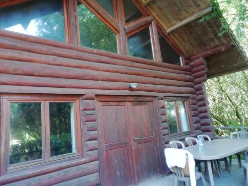 een hut met een rode deur en een tafel en stoelen bij Charming Chalet with Swimming Pool in Quend in Quend