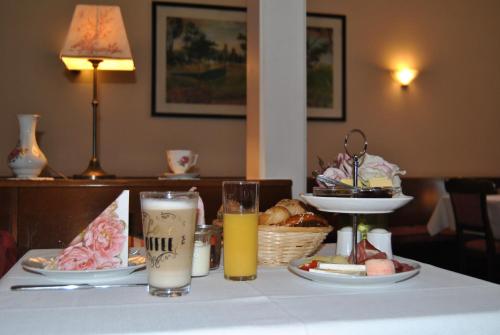un tavolo con un piatto di cibo e due bicchieri di succo di Hotel Kurpfalzstuben a Mannheim