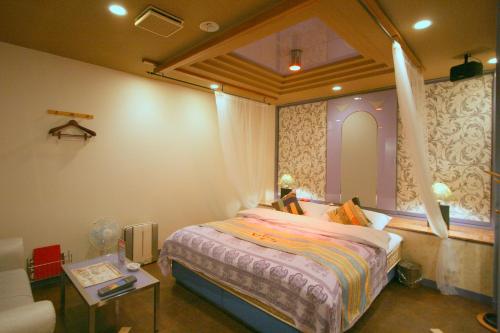 a bedroom with a bed with a window and a table at オーラリゾート四條畷 in Shijonawate