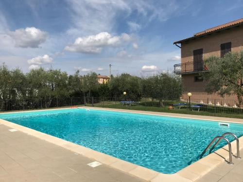 une grande piscine bleue en face d'un bâtiment dans l'établissement Agriturismo Azienda Agricola La Roccaia, à San Gimignano
