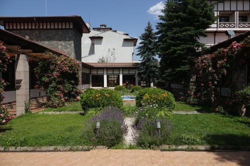 ein Garten vor einem Haus mit Blumen in der Unterkunft Спа Хотел Орфей in Dewin