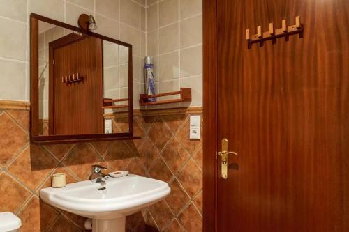 ein Badezimmer mit einem Waschbecken und einer Holztür in der Unterkunft Ca la Gloria in Vilabertrán