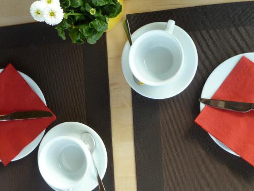 a table with white plates and red napkins on it at Haus Achtern Diek in erster Reihe am Meer in Fehmarn