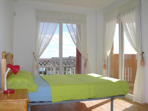 1 dormitorio con cama verde y balcón en Los Miradores Del Puerto - 3207, en La Manga del Mar Menor