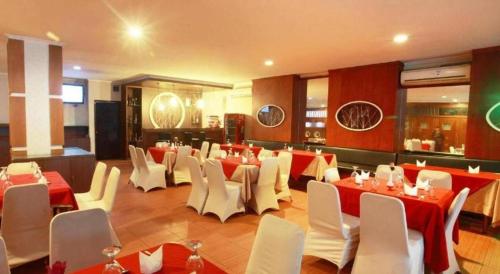 een restaurant met rode en witte tafels en witte stoelen bij Alexander Hotel Tegal in Tegal