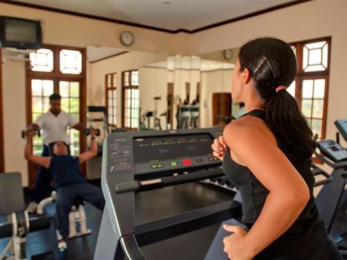 a woman exercising in a gym with two men at Mount Lavinia Hotel in Mount Lavinia