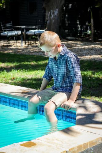 a young boy sitting on the edge of a swimming pool at Palm La Vie in Worcester