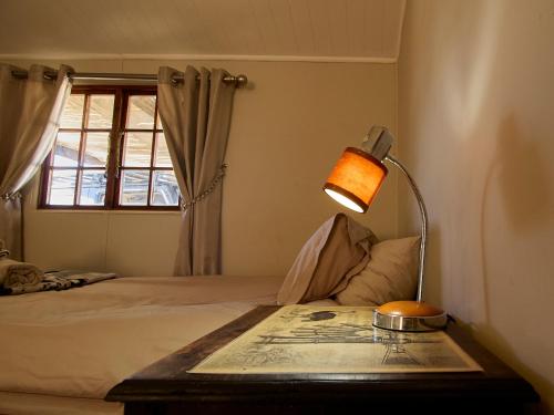 a bedroom with a bed with a table and a lamp at Jagerskraal Guest Farm in Laingsburg