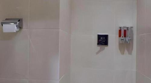 a white bathroom with a toilet paper dispenser on a wall at Tropical Point Hotel Syariah in Pipulu
