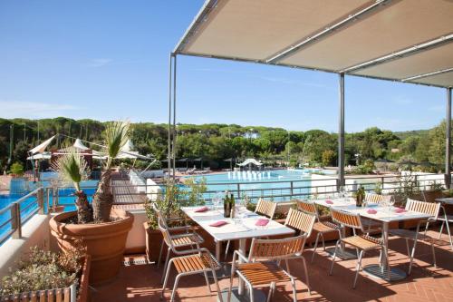 a patio with tables and chairs next to a pool at Camping Village Rocchette in Castiglione della Pescaia