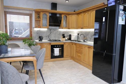 a kitchen with wooden cabinets and a black refrigerator at Садиба "Hutsulyana" in Dobrovelychkivka