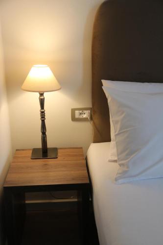 a lamp on a wooden table next to a bed at Hotel Hermes Tirana in Tirana
