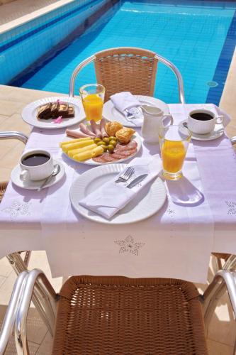 - une table blanche avec de la nourriture et des boissons à côté de la piscine dans l'établissement Irini Apartments, à Chersónissos