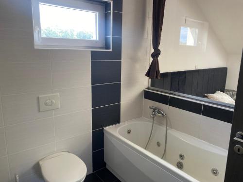 a bathroom with a toilet and a tub and a window at Apartman Lapaž 12 in Toplice Sveti Martin