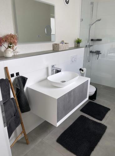 a white bathroom with a sink and a mirror at Ferienwohnung in der wunderschönen Eifel in Dankerath
