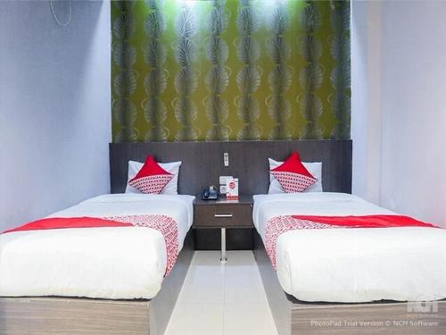 2 letti con cuscini rossi in una camera di Majestiq Hotel by TripleTree a Pekanbaru