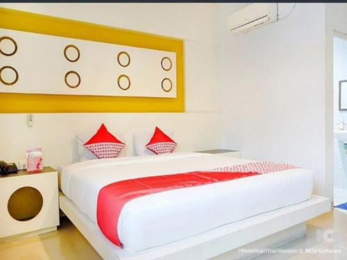 una camera da letto con un grande letto bianco con cuscini rossi di Majestiq Hotel by TripleTree a Pekanbaru