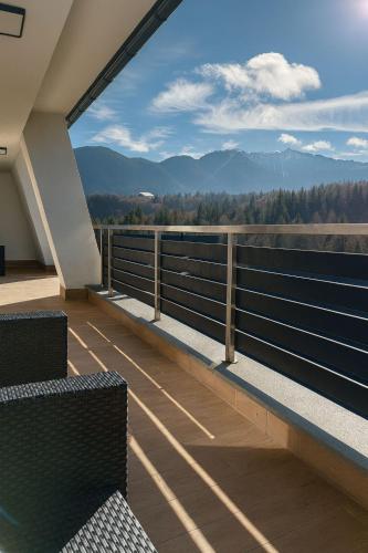 a balcony with two chairs and a view of the mountains at Luxury Penthouse-Poiana Brasov in Poiana Brasov