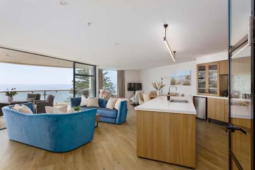 a kitchen and living room with a blue couch at Oceanside Haven Resort with Luxury Sea Views in Mount Maunganui