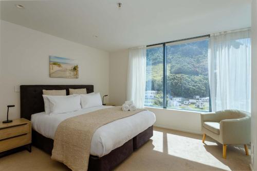 a bedroom with a bed and a chair and a large window at Oceanside Haven Resort with Luxury Sea Views in Mount Maunganui