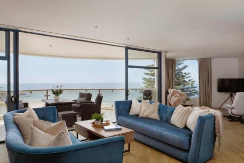 a living room with blue couches and a view of the ocean at Oceanside Haven Resort with Luxury Sea Views in Mount Maunganui