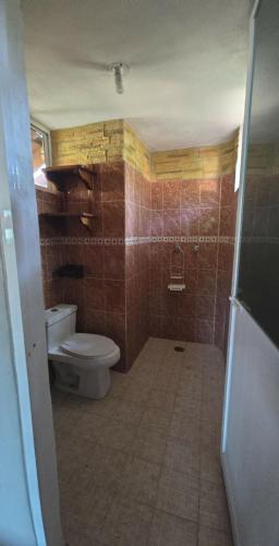 a bathroom with a toilet and a tiled floor at Casa El Limón in Zihuatanejo