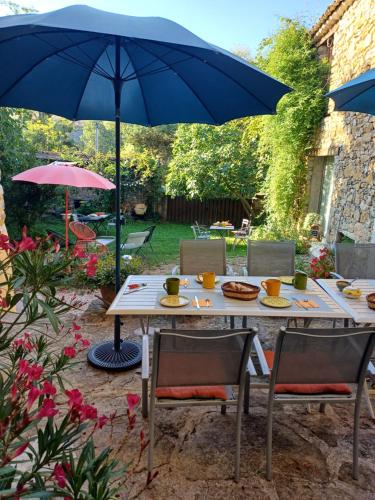 a table with two chairs and a blue umbrella at Gîte les Granges dans ferme provençale. 14 pers in Ongles