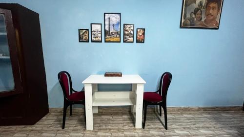 een tafel met twee stoelen en een witte tafel met foto's bij Maison De Ravi in Pondicherry
