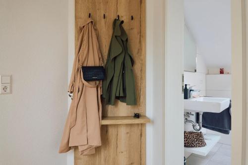 een badkamer met een houten deur met kapstokken en een wastafel bij Kapfwald Appartements in Bad Dürrheim