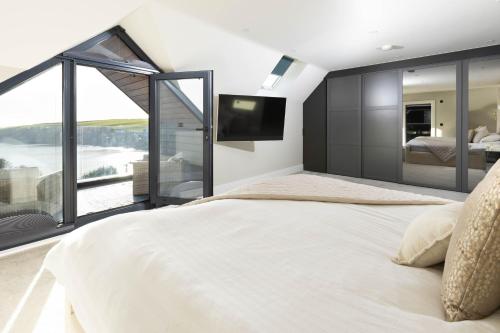 a bedroom with a large bed and a large window at Seaglass Point in Mevagissey