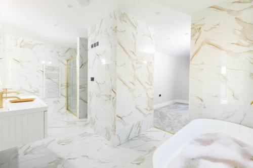 a bathroom with white marble walls and a tub and a sink at Seaglass Point in Mevagissey