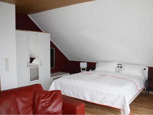 a bedroom with a white bed and a red couch at Ferienwohnung Kramer in Rüber
