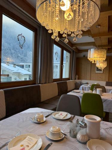 een eetkamer met tafels en stoelen en een kroonluchter bij Hotel Garni Jennewein in Mayrhofen