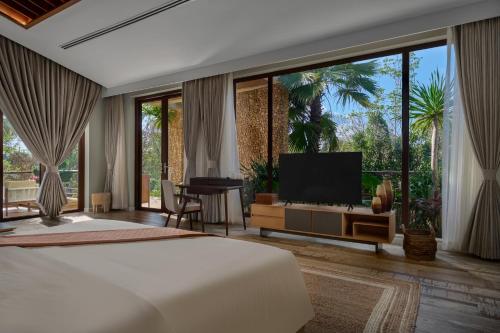 a bedroom with a bed and a flat screen tv at Samanea Wellness Resort in Phumĭ Tŭk Lŭy