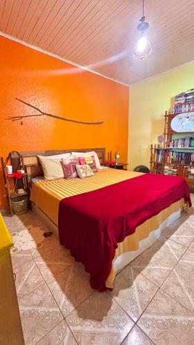 a bedroom with a large bed with an orange wall at Casa Refúgio Cataratas - Perto das Principais Atrações e do Aeroporto in Foz do Iguaçu