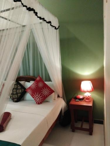 a bedroom with a bed with a canopy and a table at Green Bamboo House in Sigiriya