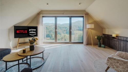 een woonkamer met een tv en een groot raam bij 2 stilvolle Ferienhäuser Südsteiermark ruhige Lage top Aussicht & Wallbox in Eibiswald